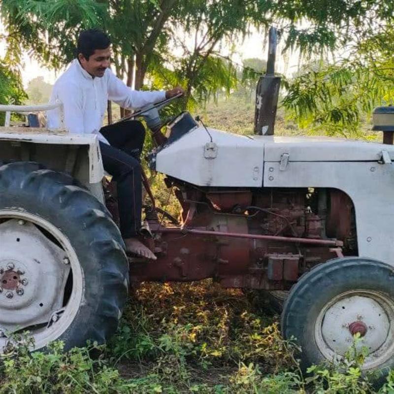 Farmer with tractor working the organic farmland at Nisarg Organic Farm, Gujarat