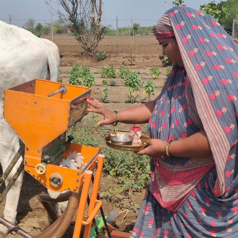 Woman operating a herb grinding machine to make fresh Ayurvedic powders at Nisarg Organic Farm